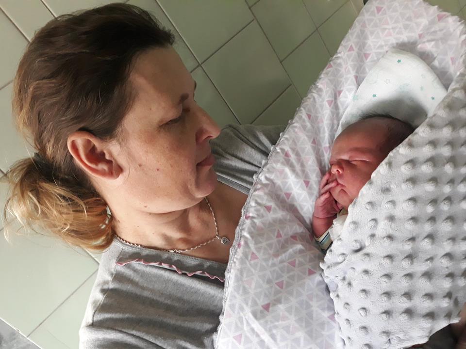 Kobieta w szpitaliu trzyma noworodka w becie i patrzy się na niego