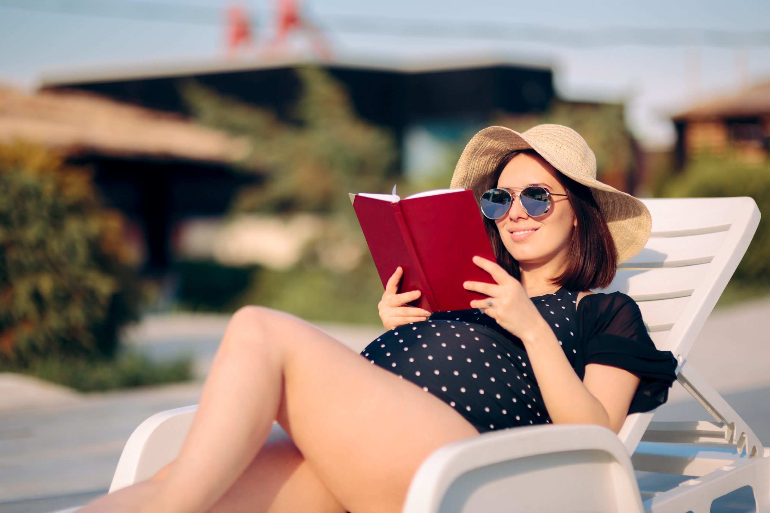 Kobieta w ciąży czytająca książkę nad basenem