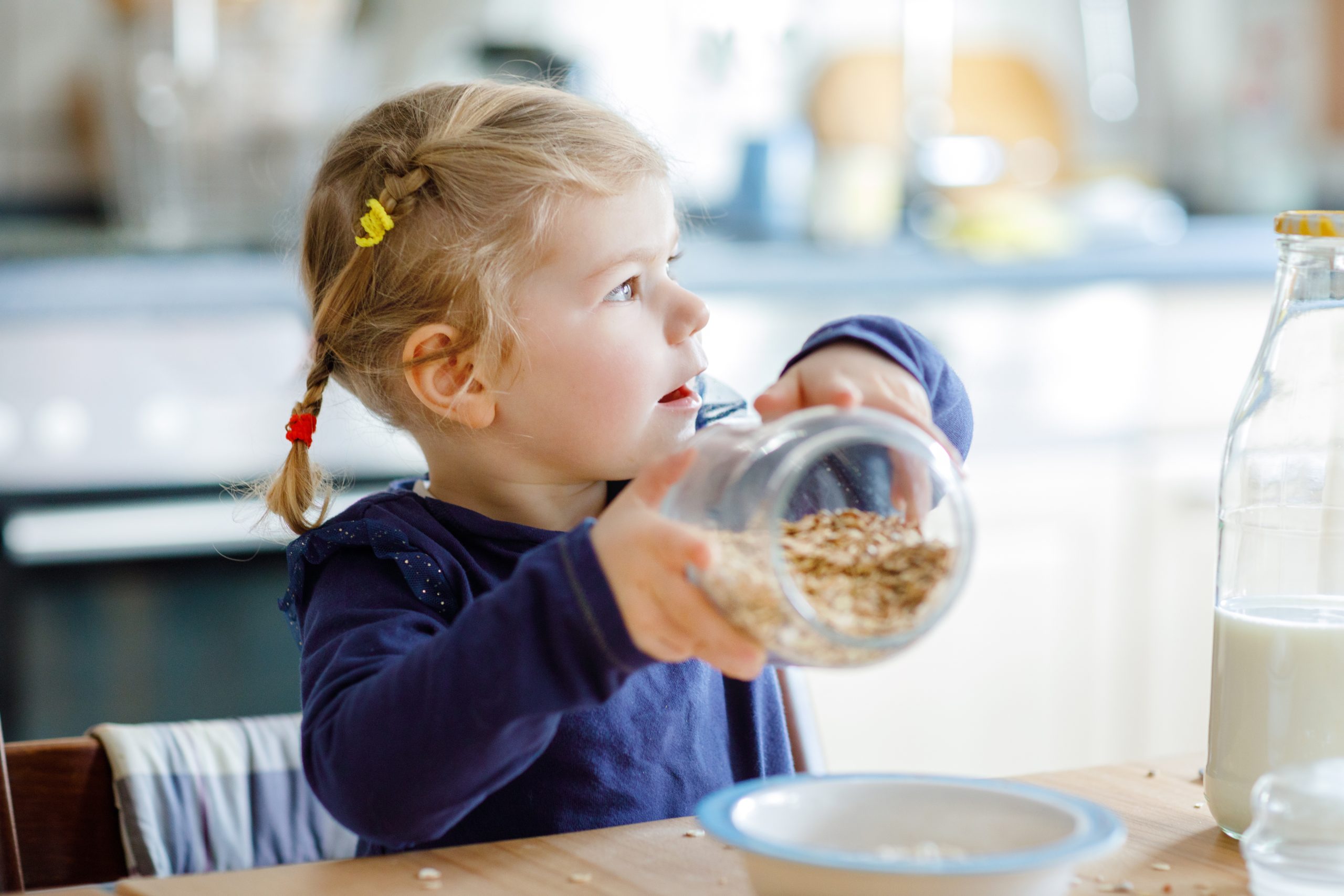 dziewczynka jedząca płatki owsiane z mlekiem na śniadanie