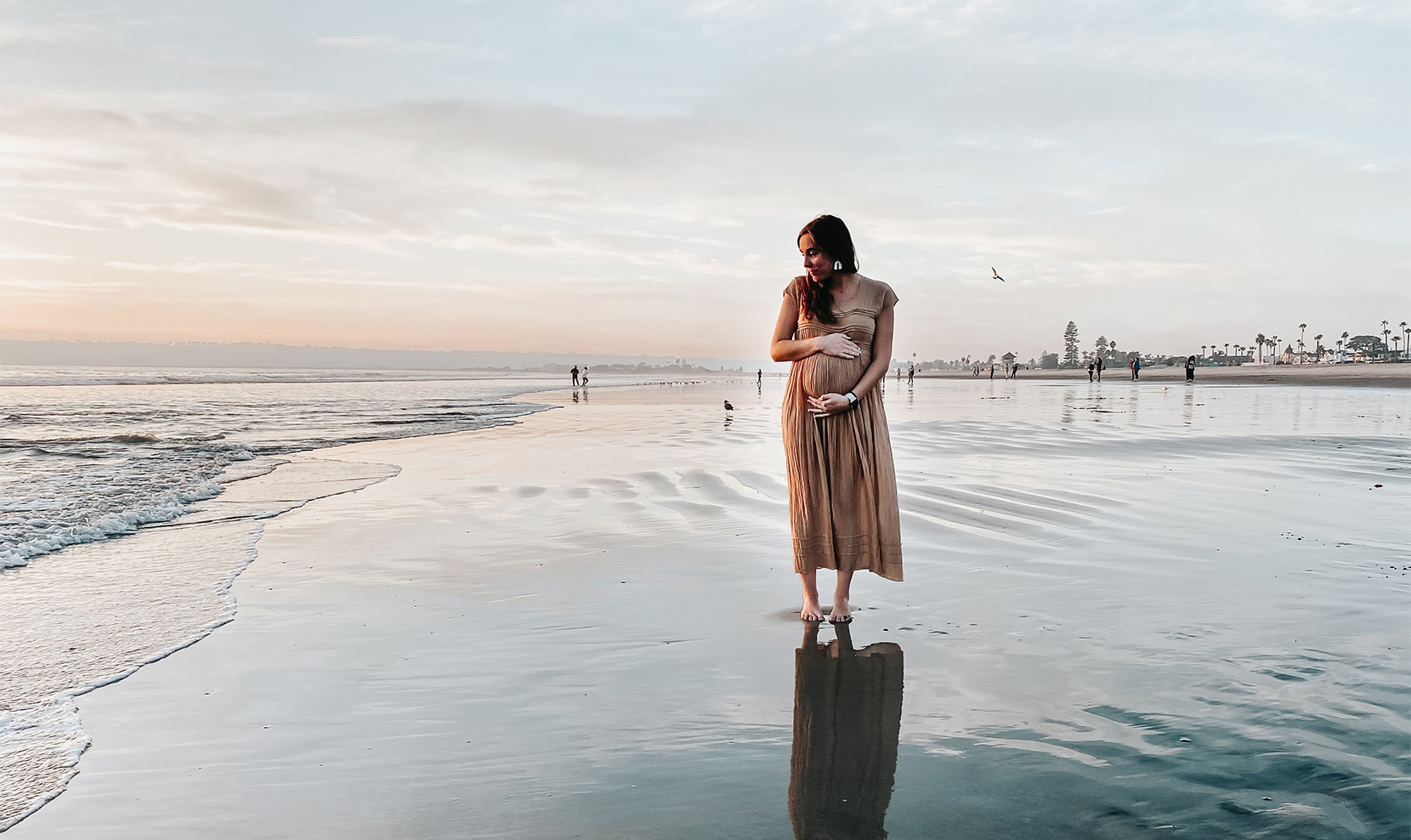 Kobieta w ciąży spaceruje nad brzegiem morza