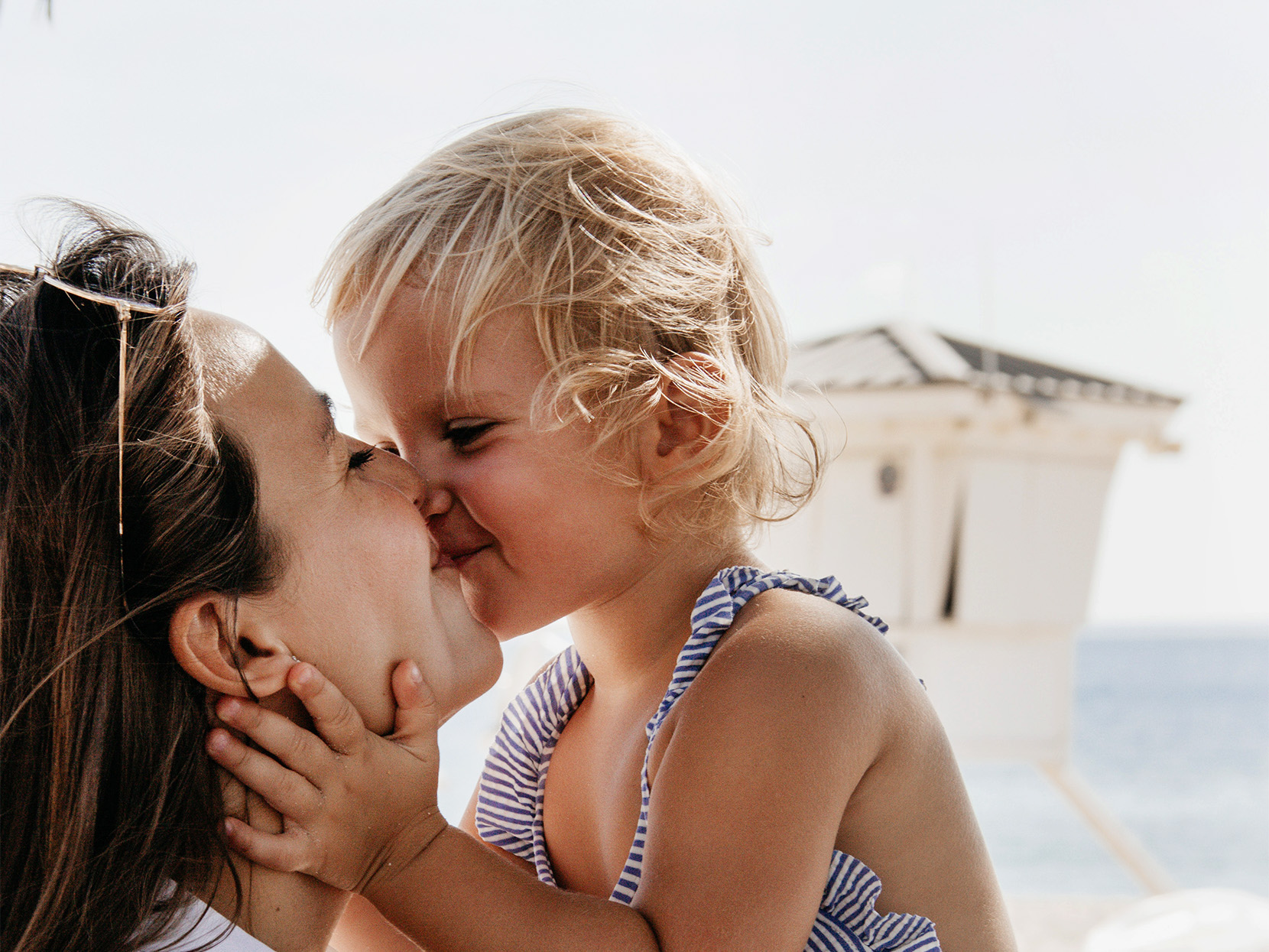 Rodzicielstwo bliskości opiera się na budowaniu głębokiej emocjonalnej więzi między opiekunem a dzieckiem - na zdjęciu mama i córka dające sobie buziaka HelloMama